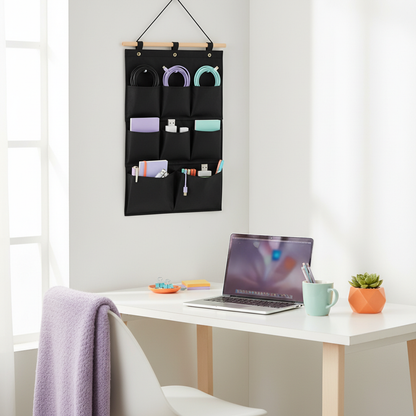 Black hanging wall organizer holding cables, notebooks and desk supplies beside a laptop
